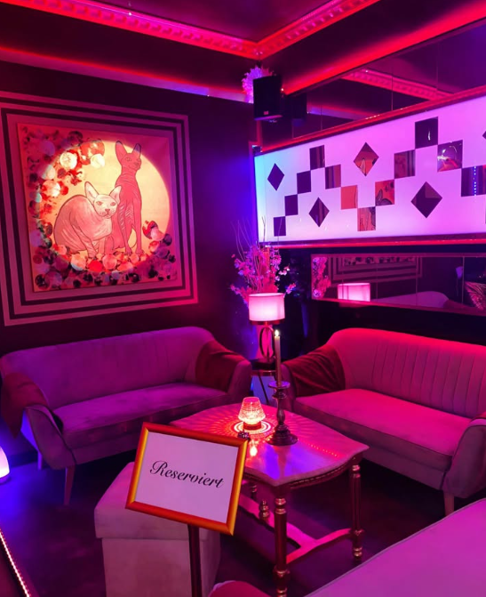 Reservierter Loungebereich mit rosa Neonlicht und Kunst an der Wand